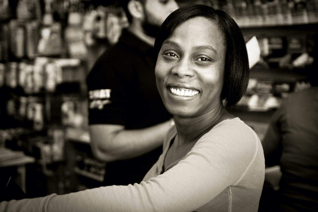 An African American woman with chin-length black hair smiles broadly at the camera.